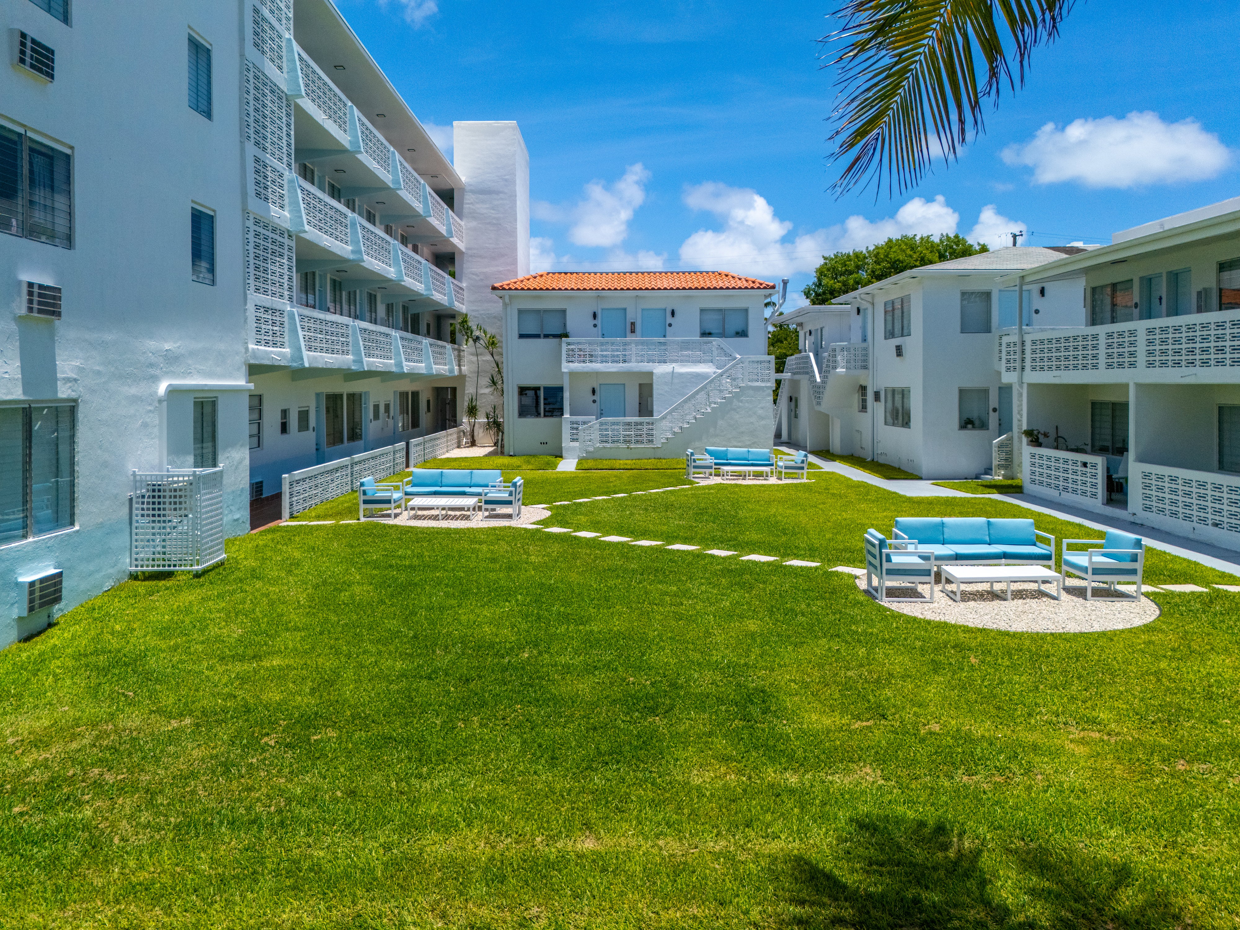 A sunny day at the courtyard of a white apartment building.